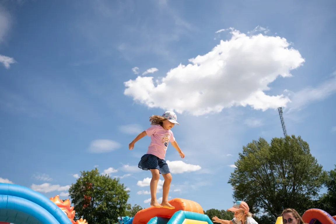 Niña saltando en el hinchable gigante con el cielo de fondo